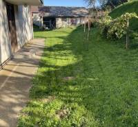 Rodinný dům v Hajnáčce s trávníkem a zahradním domkem na dvoře.