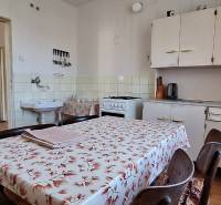 Kuchyně v rodinném domě s jídelním stolem, linkou a sporákem.