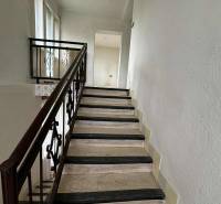 Schodiště v rodinném domě s kovovým zábradlím a okny zajišťuje přirozené světlo.