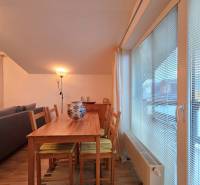 Jídelní stůl s pěti židlemi a lampou v rekreačním apartmánu s podlahou s dřevěným dekorem.