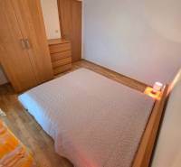 Ložnice v rekreačním apartmánu s postelí a nábytkem na podlaze s dřevěným dekorem.