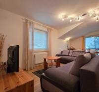 Obývací pokoj v rekreačním apartmánu s pohodlnými pohovkami a podlahou s dřevěným dekorem.