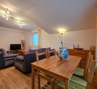 Obývací pokoj v rekreačním apartmánu s podlahou s dřevěným dekorem, sedačkou a jídelním stolem.