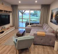 Obývací pokoj v rodinném domě s podlahou s dřevěným dekorem, rohovou pohovkou a televizorem.