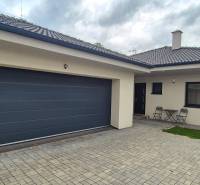 Rodinný dům ve Studience se dvěma židlemi a stolkem na dlážděném dvoře.