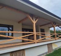 Rodinný dům ve Studience má terasu s dřevěným zábradlím a přilehlým trávníkem.