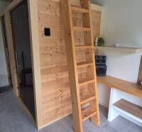 Interiér rodinného domu s dřevěnou saunou, žebříkem a stereo zařízením.