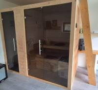 Interiér rodinného domu se saunou, ventilátorem a umyvadlem na dřevěném stole.