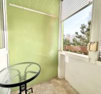 Balkón so stolíkom v 2-izbovom byte s výhľadom na zeleň.