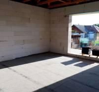 Stavba rodinného domu v Radavě s pohledem na neomítnuté stěny a okolní krajinu.