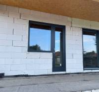 Nedokončená fasáda rodinného domu v Radavě s plastovými dveřmi a okny.