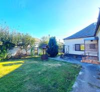 Rodinný dům v Nedede s upravenou zahradou, trávníkem a altánem vedle domu.