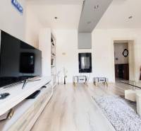 Obývací pokoj v rodinném domě s televizí a podlahou s dřevěným dekorem.