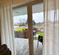 Interiér rodinného domu s výhledem na terasu a zahradu, podlaha s dřevěným dekorem.