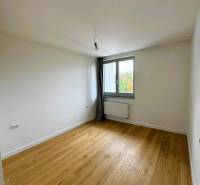 Místnost s podlahou s dřevěným dekorem, okno, radiátor v rodinném domě.