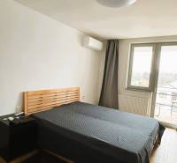 Ložnice s postelí, nočním stolkem a podlahou s dřevěným dekorem v rodinném domě.