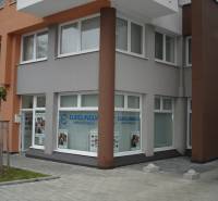 Obchodní prostory na Komárnické ulici v Bratislavě - Ružinov s velkými okny a reklamním nápisem.