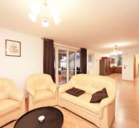 Obývací pokoj rodinného domu s krémovou sedačkou a podlahou s dřevěným dekorem.