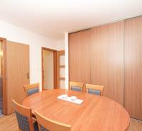 Jídelní kout v rodinném domě s dřevěnými doplňky a koupelnou v pozadí.