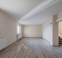 Prostorná místnost s podlahou s dřevěným dekorem a schodištěm v rodinném domě.