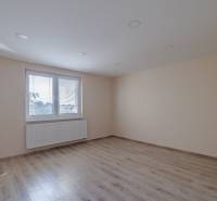 Pokoj s podlahou s dřevěným dekorem a velkým oknem v rodinném domě.