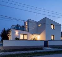 Rodinný dům na Trnovecké ulici v Trnovci nad Váhom osvětlený za soumraku.