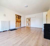 Interiér rodinného domu s podlahou s dřevěným dekorem a bílými stěnami.