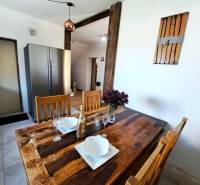 Jídelní stůl s doplňky a lednička v kuchyni rodinného domu.