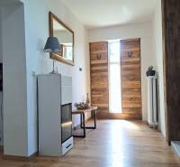 Interiér s dřevěnými vstupními dveřmi a podlahou s dřevěným dekorem v rodinném domě.