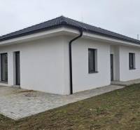 Rodinný dům v Cíferi se šikmou střechou a dlážděnou terasou na zahradě.