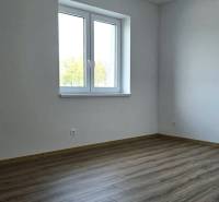 Pokoj v rodinném domě s podlahou s dřevěným dekorem a bílými stěnami.