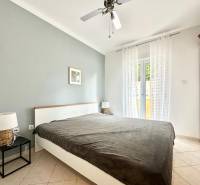 Ložnice v rekreačním apartmánu s manželskou postelí a nočními stolky.