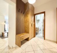 Chodba rekreačního apartmánu s pračkou a věšákovou stěnou s dřevěným dekorem.