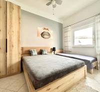 Světlá ložnice s dřevěným nábytkem, dvojlůžkem a obrazem v rekreačním apartmánu.