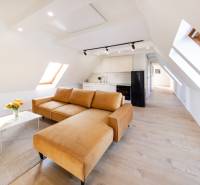 Obývací pokoj v 2-pokojovém bytě s koženou sedačkou a podlahou s dřevěným dekorem.