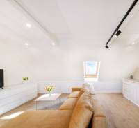 Světlý obývací pokoj s béžovou pohovkou, podlahou s dřevěným dekorem a střešním oknem.