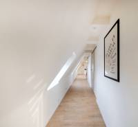 Chodba v 2-pokojovém bytě s podlahou s dřevěným dekorem, střešním oknem a obrazem na stěně.