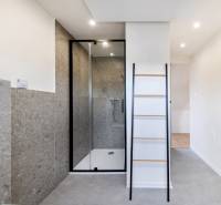 Koupelna v 2pokojovém bytě s prostorným sprchovým koutem a žebříkovým nábytkem.