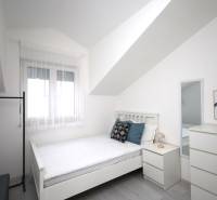 Světlý pokoj s postelí, zrcadlem a dekoracemi v rekreačním apartmánu.