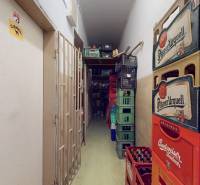 Úzké chodby v obchodních prostorách se skladovanými pivními přepravkami.