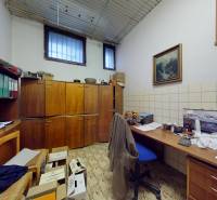 Kancelář s dřevěnými skříňkami, pracovním stolem a poličkami, použitá dlažba s geometrickým vzorem.