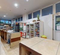 Interiér obchodních prostor s různým zbožím a osvětlením, včetně nápojů a potravin.