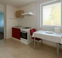 Kuchyně s červenou skříňkou, stolem a dvěma židlemi v rodinném domě.