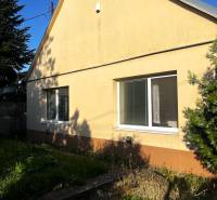 Rodinný dům v Diakovcích se šikmou střechou a žlutou fasádou, obklopený zelení.