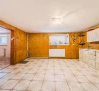 Kuchyně v rodinném domě s dřevěným dekorem a keramickou dlažbou.