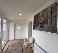 Interiér 1-pokojového bytu s podlahou s dřevěným dekorem, skleněnými dveřmi a uměním na stěně.