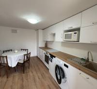 Kuchyně v 1-pokojovém bytě s podlahou s dřevěným dekorem a jídelním stolem.