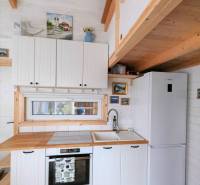 Kuchyně v rodinném domě s bílými skříňkami, dřevěným dekorem a barevnou dlažbou.