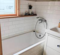 Koupelna v rodinném domě s vestavěnou vanou a bílými kachličkami.