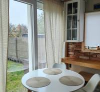 Jídelní kout v rodinném domě s podlahou s dřevěným dekorem, cihlovou stěnou a velkými okny.